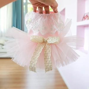 Close-up of pink pet lace dress featuring a cream bow and ruffled organza layers