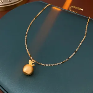 Minimalist 18k gold plated necklace with matte apple pendant on green jewelry box