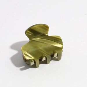 Detail showing the olive green marble texture and sturdy teeth of the hair claw clip