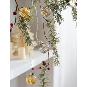 Christmas glass pumpkin LED string lights in gold and silver hanging on a pine tree