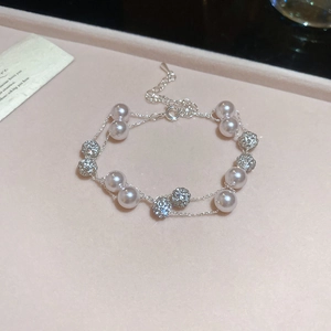 Detail view of double-layered pearl necklace with crystal balls on pink velvet