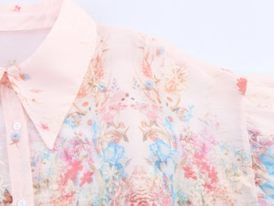 Close-up of floral embroidery and soft pink flower print on the collared shirt fabric