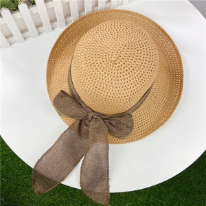 Detail view of woven straw hat featuring a brown mesh bow and rustic frayed edge design