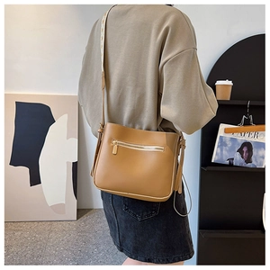 Chic khaki small tote bag worn by a model in a stylish interior with decorative patterns
