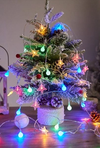 Close-up of colorful LED star and ball string lights on a snowy Christmas tree