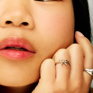Elegant silver bow-shaped metal ring shown in a professional lifestyle close-up on model