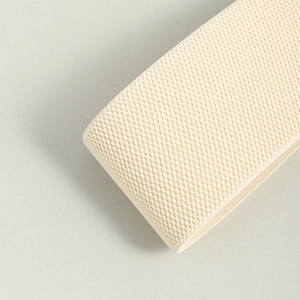 Close-up of beige woven elastic belt roll showing fine texture and detailed craftsmanship
