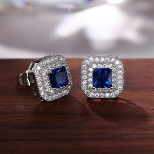 Macro shot of silver square earrings with deep blue center stone and pave zircon details
