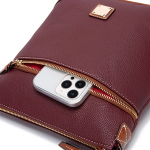 Macro shot of dark red lychee leather crossbody bag with smartphone in front pocket