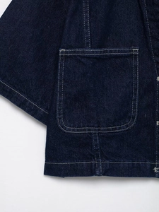 Detailed close-up of dark blue denim fabric with white contrast stitching and pocket details