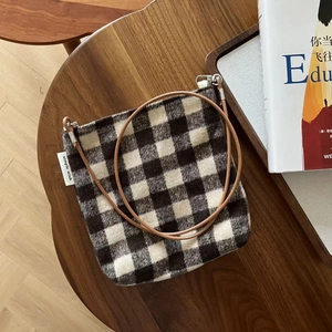 Detail of black and white houndstooth wool crossbody bag with brown leather strap