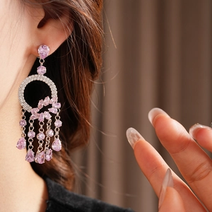 Close-up of silver tassel earrings with pink pear-cut zircon crystals on a female model