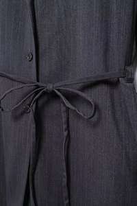 Detail of waist design on dark grey pinstripe blazer featuring a fabric tie belt