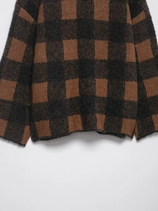 Detailed macro view of the brown and black checkered knit texture on the cardigan cuff