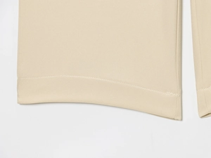 Détail de l'ourlet et de la texture sergée d'un pantalon large de couleur beige