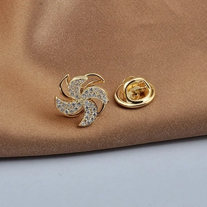 Macro detail of gold windmill brooch with sparkling zircon and matching butterfly clasp