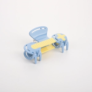 Close-up of color-blocked blue and yellow hair claw clip with gaming D-pad design details
