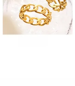 Macro shot of two polished 18K gold-plated Cuban link rings on a textured glass surface