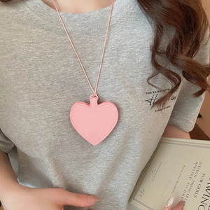Close-up of pink heart leather pendant accessory worn over a casual grey t-shirt