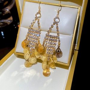 Detail of elegant gold tassel earrings with rhinestones and feather leaves in a jewelry box