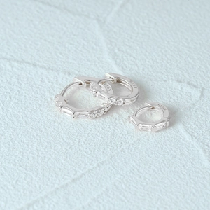 Macro shot of S925 sterling silver hoop earrings set with zircon on blue fabric