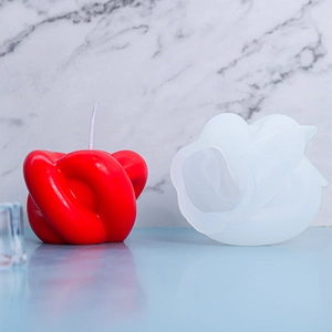 Détail du moule en silicone pour bougie à nœud et bougie rouge terminée sur un piédestal