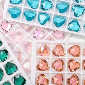 Detailed view of 12mm heart-shaped crystal glass rhinestones in multiple colors on trays