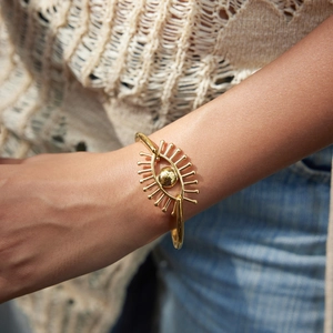 Bracelet jonc œil maléfique en acier doré 18k porté par un mannequin, style décontracté