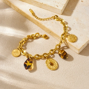 Vintage gold chain bracelet with tiger eye beads and star pendants on a stone surface