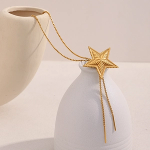 Detail of 18K gold-plated star pendant necklace with radial texture on a white vase