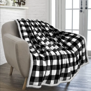 Detail of buffalo plaid flannel blanket with sherpa lining draped on a modern armchair