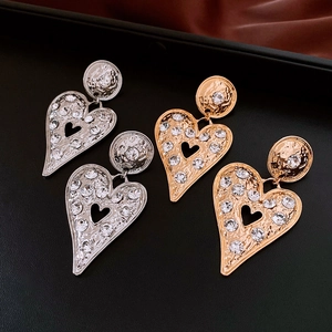 Macro view of gold and silver textured heart earrings with sparkling rhinestones