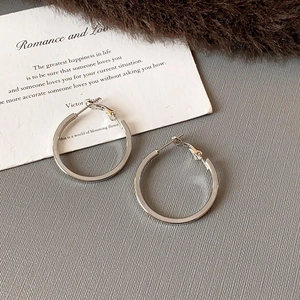 Close-up of elegant silver hoop earrings with a polished finish on textured fabric
