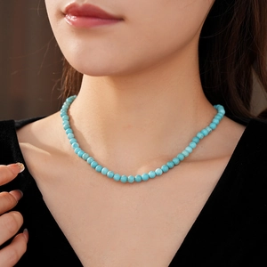 Close-up of minimalist turquoise beaded necklace worn on model for elegant style