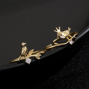 Macro detail of bird and branch ring set in gold finish with sparkling zircons