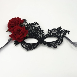 Close-up of black lace masquerade mask with vibrant red roses and silk ribbon ties