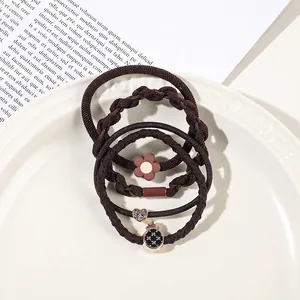 Detail of coffee brown elastic hair ties set with heart and flower charms on a white plate