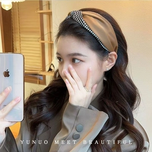 Detail of wide twist headband featuring brown satin and black and white houndstooth pattern