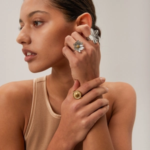 Bagues fleurs en acier inoxydable et bague pièce soleil dorée sur un mannequin
