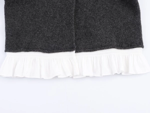 Detailed close-up of dark grey knit fabric with white poplin pleated hem detailing