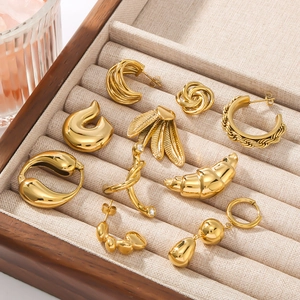 Collection of golden titanium steel earrings with various minimalist designs on a tray