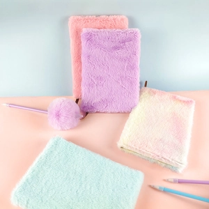 Dettaglio di quaderni di peluche viola, rosa, blu e arcobaleno con penne a sfera con pompon