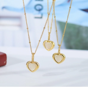 Macro detail of gold heart necklaces with natural shell inlay on satellite chains