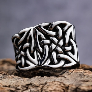 Detailed close-up of a wide Celtic knot engraved band on a rustic wooden base
