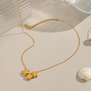 Classic gold star necklace with three pentagram pendants on a beige background