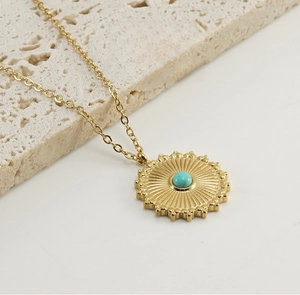 Close-up of 18k gold plated necklace with turquoise pendant on a natural rock