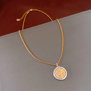Detail of two-tone gold and silver coin pendant necklace with intricate floral engraving