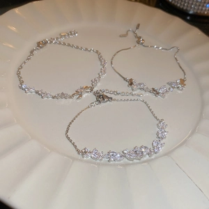 Detail of silver-tone bracelets with butterfly, wave knot, and marquise zircon designs
