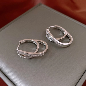 Detailed view of silver double-layered huggie hoop earrings with sparkling zircon accents