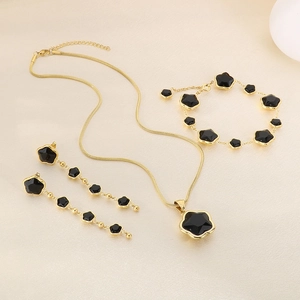 Detail of gold-plated jewelry set featuring black four-leaf clover tassels and snake chain